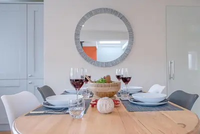 a dining room table with a mirror and wine glasses at Festival House, Snape in Saxmundham