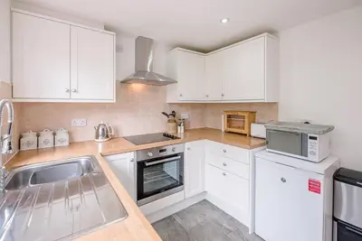 a kitchen with white cabinets and a sink at North Cottage, Alderton in Woodbridge