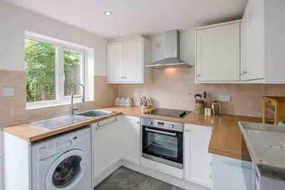 a kitchen with white cabinets and a washing machine at North Cottage, Alderton in Woodbridge