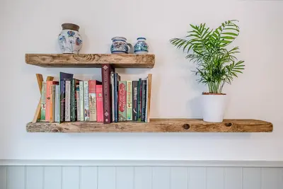 a shelf with books and a potted plant on a wall at North Cottage, Alderton in Woodbridge