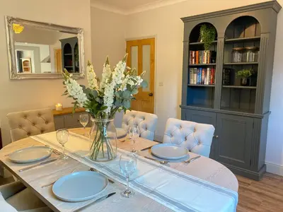 a dining room table with a vase of flowers on it at Refurbished Victorian Villa- Free Parking- Sleeps6 in Bury Saint Edmunds