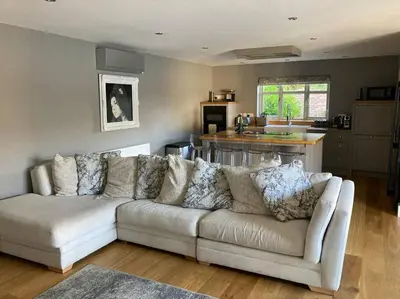 a living room with a white couch and a kitchen at The Oaks, Luxury 2 bedroom cottage in a peaceful location in Haughley