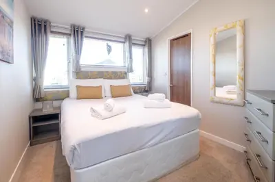a bedroom with a large white bed with two towels on it at Chelsea Lodge - Aldeburgh Coastal Cottages in Sizewell