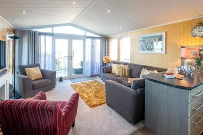 a living room with a couch and a table at Chelsea Lodge - Aldeburgh Coastal Cottages in Sizewell