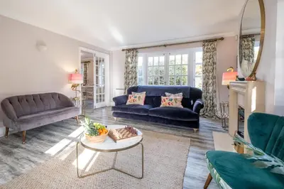 a living room with a blue couch and a table at 1 Sanctuary Court - Aldeburgh Coastal Cottages in Thorpeness