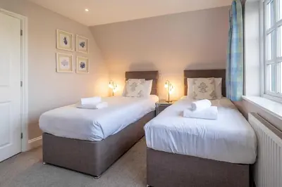 two twin beds in a room with two windows at 1 Sanctuary Court - Aldeburgh Coastal Cottages in Thorpeness