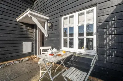 a table and chairs on a porch with a window at 1 Sanctuary Court - Aldeburgh Coastal Cottages in Thorpeness