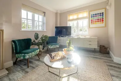 a living room with two chairs and a table and a tv at 1 Sanctuary Court - Aldeburgh Coastal Cottages in Thorpeness