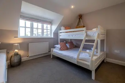 a bedroom with two bunk beds and a window at 1 Sanctuary Court - Aldeburgh Coastal Cottages in Thorpeness