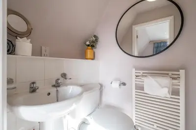 a bathroom with a sink and a toilet and a mirror at 1 Sanctuary Court - Aldeburgh Coastal Cottages in Thorpeness