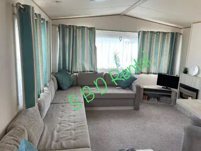 a living room with a couch and a tv at Summer Breeze Deluxe Caravan Rental in Saint Osyth