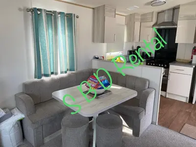 a living room with a couch and a table at Summer Breeze Deluxe Caravan Rental in Saint Osyth
