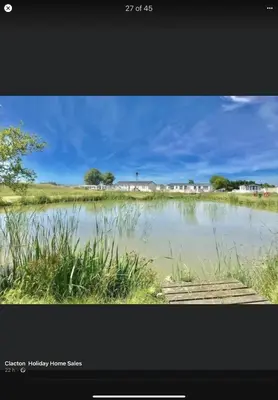 a picture of a lake with houses in the background at Summer Breeze Deluxe Caravan Rental in Saint Osyth