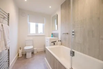a white bathroom with a tub and a toilet at The Artist's House, Orford in Orford