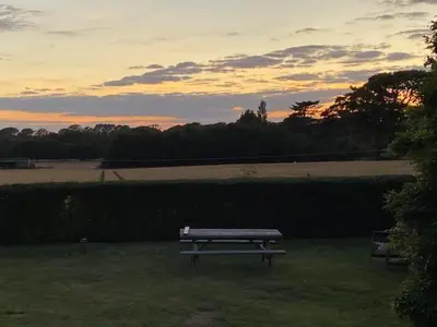 a park bench in a field with a sunset in the background at The Artist's House, Orford in Orford