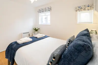 a bedroom with a large white bed with pillows at The Britten - Aldeburgh Coastal Cottages in Aldeburgh