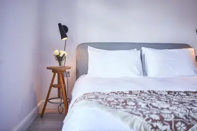 a bed with white sheets and a table with a lamp at SEALOFT, Aldeburgh , Stay in Suffolk in Aldeburgh