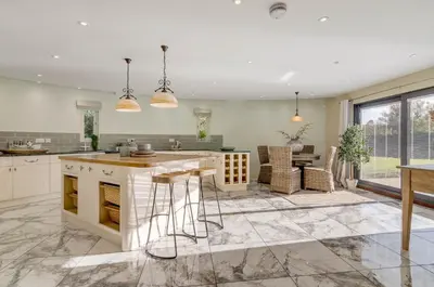 a kitchen with white cabinets and a table and chairs at 5 Bedroom House in Larling, near Thetford in Norwich