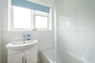 a white bathroom with a sink and a window at Kittiwake, Aldeburgh - Aldeburgh Coastal Cottages in Aldeburgh