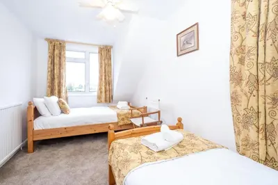 a bedroom with two beds and a window at Kittiwake, Aldeburgh - Aldeburgh Coastal Cottages in Aldeburgh