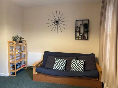 a living room with a blue couch and a clock on the wall at Cosy central 1 bedroom flat near city centre & station in Cambridge