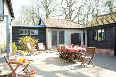 a patio with a table and chairs and a house at Yew Tree Farm Barn, Worlingworth in Worlingworth
