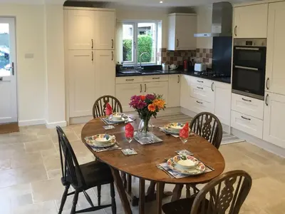 a kitchen with a wooden table with chairs and flowers at Hedgeways in Fordham