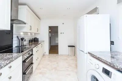 a kitchen with white cabinets and a refrigerator at The White & Warm, Free Parking & Wifi, 8 beds in Colchester