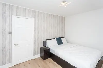 a white bedroom with a bed and a ceiling fan at The White & Warm, Free Parking & Wifi, 8 beds in Colchester