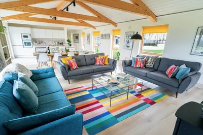 a living room with blue couches and a colorful rug at Willow Cottage at Gravel Farm in Stretham