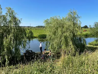three people standing in the water under a tree at Willow Cottage at Gravel Farm in Stretham