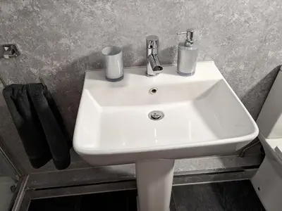 a white sink in a bathroom with black towels at Cosy Cabin in Stock