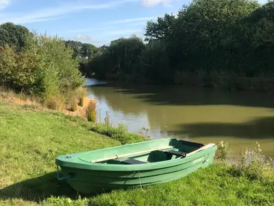 a green boat sitting on the side of a river at Cosy Cabin in Stock