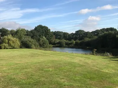 a grassy field with a river in the background at Cosy Cabin in Stock