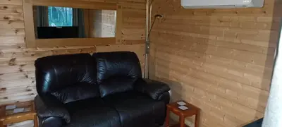 a black leather couch in a room with a television at Cosy Cabin in Stock