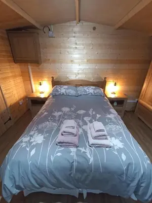 a bed in a wooden room with towels on it at Cosy Cabin in Stock