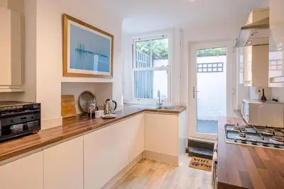 a kitchen with white cabinets and a large window at 232a High Street, Aldeburgh in Aldeburgh