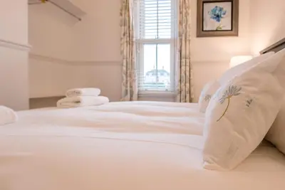 a white bed with white sheets and a window at 232a High Street, Aldeburgh in Aldeburgh