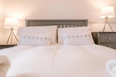 a white bed with white pillows and two lamps at 232a High Street, Aldeburgh in Aldeburgh