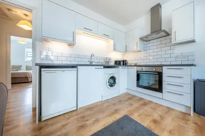 a kitchen with white cabinets and a washer and dryer at 2BR Apartment Near Stansted Airport & Bishop Stortford in Bishops Stortford
