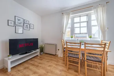 a living room with a table and chairs and a tv at 2BR Apartment Near Stansted Airport & Bishop Stortford in Bishops Stortford