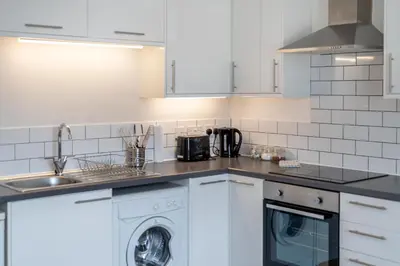 a kitchen with white cabinets and a washer and dryer at 2BR Apartment Near Stansted Airport & Bishop Stortford in Bishops Stortford