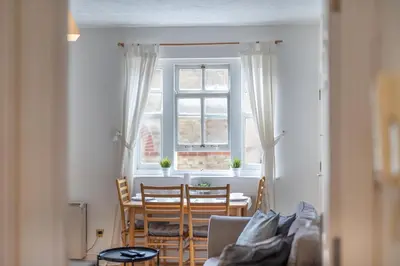 a living room with a table and chairs and a window at 2BR Apartment Near Stansted Airport & Bishop Stortford in Bishops Stortford