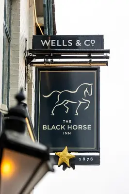 a sign for the black horse inn on a building at The Black Horse in Swaffham Bulbeck