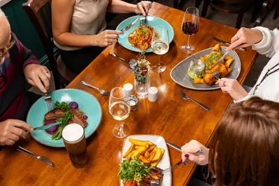 a group of people sitting at a table with plates of food at The Black Horse in Swaffham Bulbeck