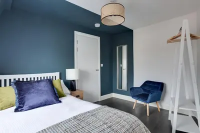 a bedroom with blue walls and a bed and a blue chair at Cosy Chelmsford Apartment - Free Allocated Parking in Chelmsford