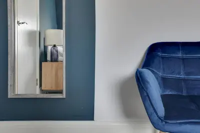a blue chair in a room with a mirror at Cosy Chelmsford Apartment - Free Allocated Parking in Chelmsford
