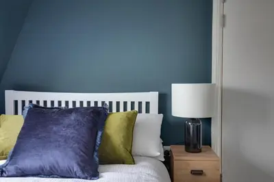 a bedroom with blue walls and a bed with pillows at Cosy Chelmsford Apartment - Free Allocated Parking in Chelmsford