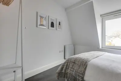 a white bedroom with a bed and a window at Cosy Chelmsford Apartment - Free Allocated Parking in Chelmsford