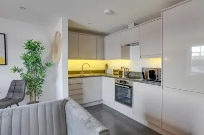 a kitchen with white cabinets and a couch at Cosy Chelmsford Apartment - Free Allocated Parking in Chelmsford
